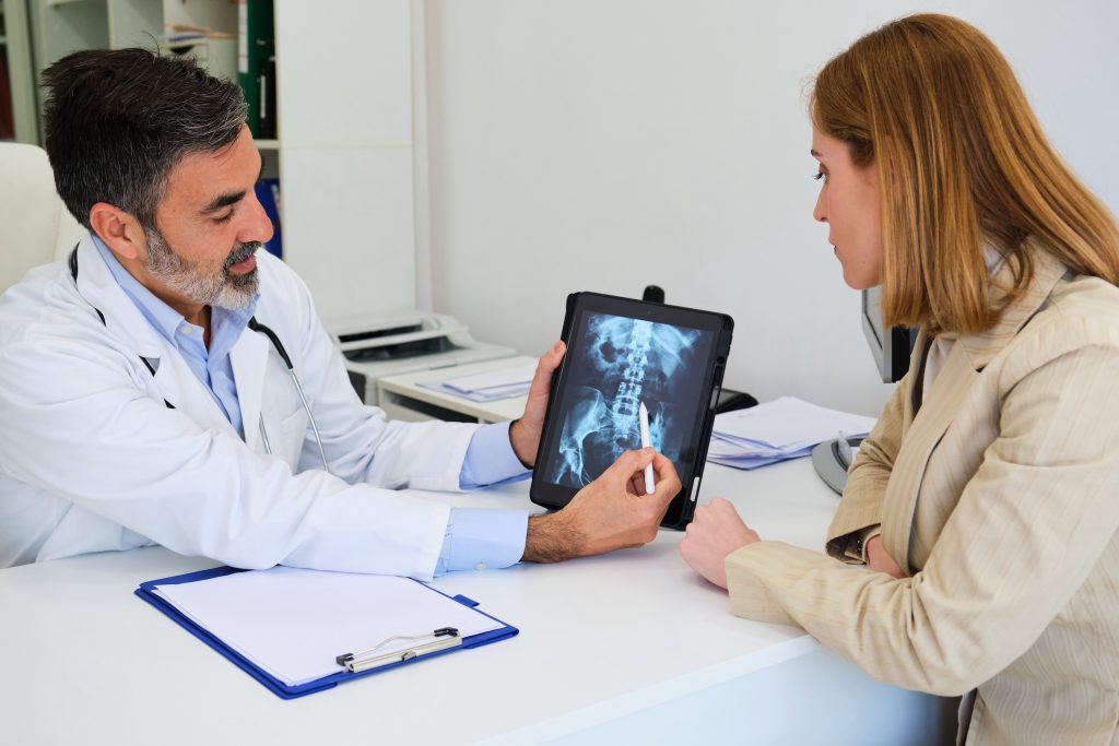 doctor explaining x ray to his female patient after surgery for a broken hip.